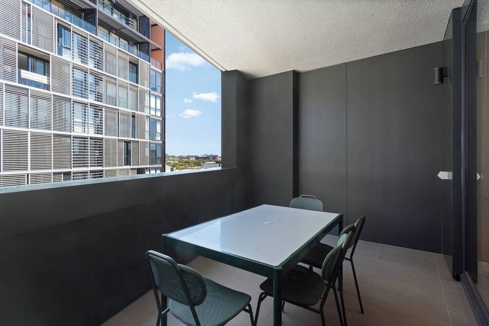 Enjoy relaxed meals or morning coffee on the spacious balcony, where outdoor dining and open skies create an easy extension of the living space.