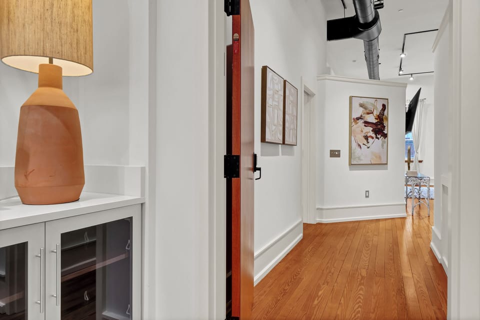 Step into your stylish hallway where warm hardwood floors guide you past curated artwork and thoughtful design touches.