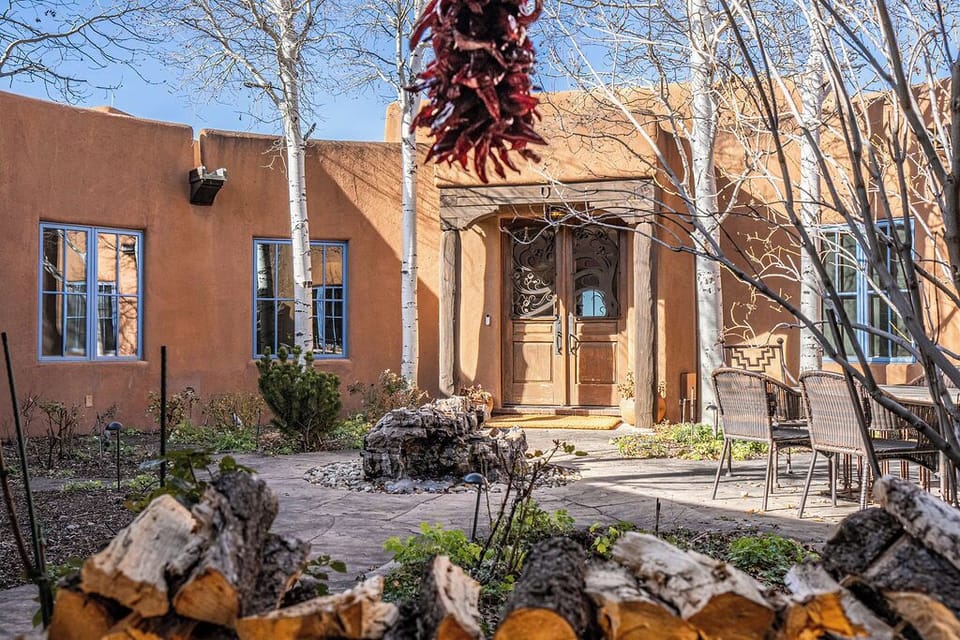Southwestern adobe architecture with decorative entrance and natural landscaping in the courtyard area.