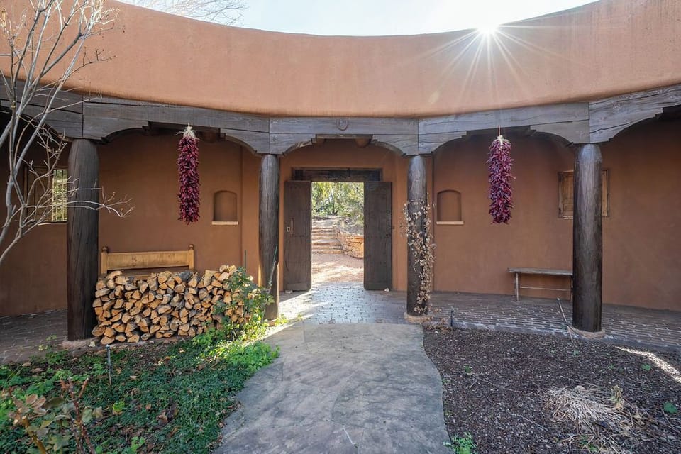 Adobe-style entrance with wooden beams and rustic charm welcomes guests to this distinctive southwestern retreat.