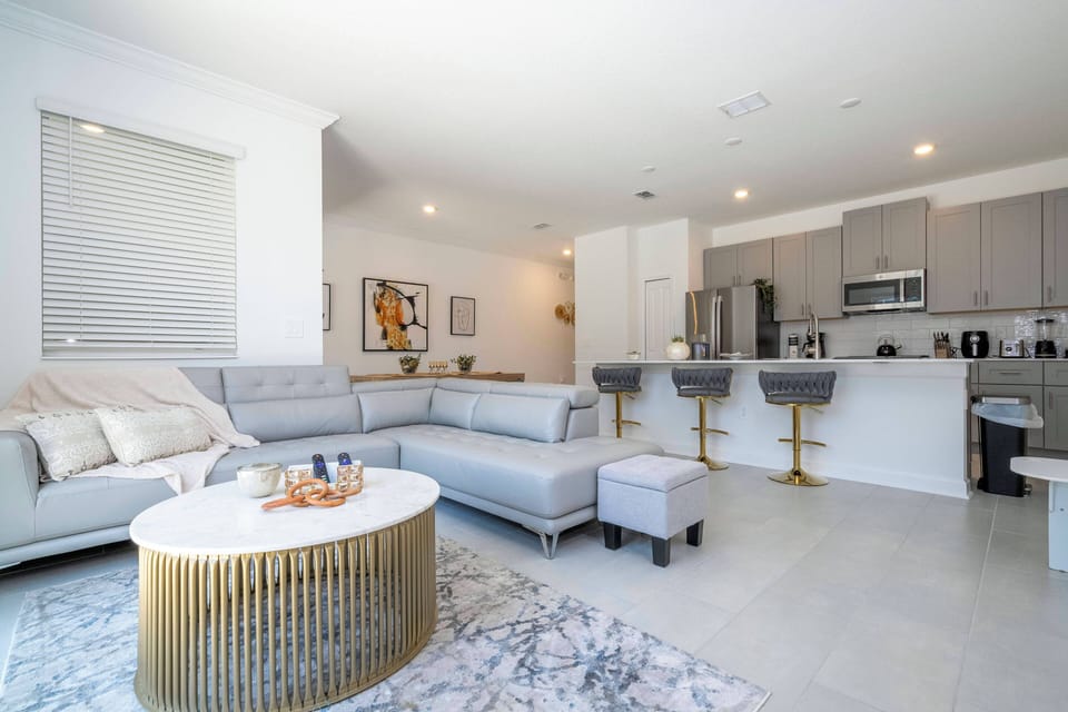 Bright and airy, this living space combines comfort and style with a plush gray sectional and a chic gold coffee table. The sleek kitchen, featuring stainless steel appliances, invites you to embark on culinary adventures.