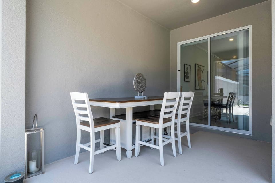This bright dining area features a sleek white table and sturdy chairs, perfect for meals or games. Large sliding doors bring in natural light and connect you with beautiful views, creating a welcoming, contemporary atmosphere.