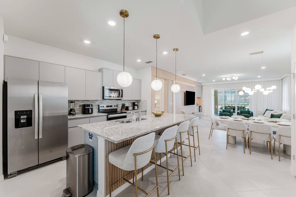 Experience a modern kitchen featuring sleek stainless steel appliances and elegant white cabinetry. The spacious island with stylish bar stools creates a perfect casual dining spot in a warm, inviting atmosphere filled with.