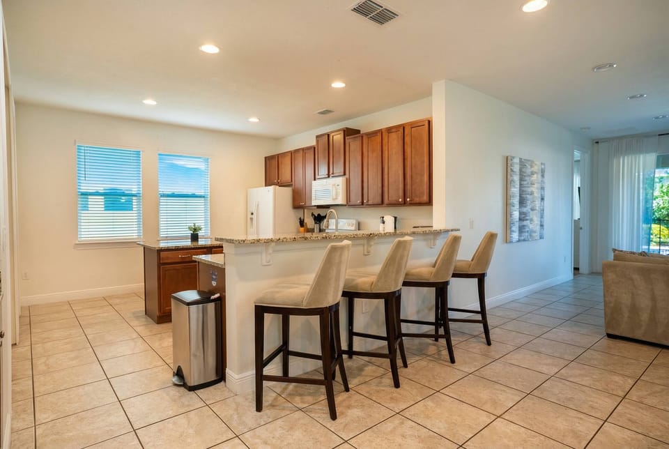 This bright kitchen, with warm wooden cabinets and sleek tile flooring, invites your culinary creativity. Enjoy casual meals at the stylish bar stools, perfectly placed to soak in the natural light streaming through the windows.