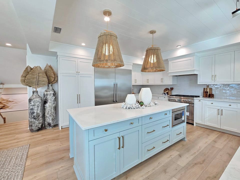 Whip up memorable meals in this stunning coastal-inspired kitchen featuring a spacious island, premium appliances, and stylish woven light fixtures.