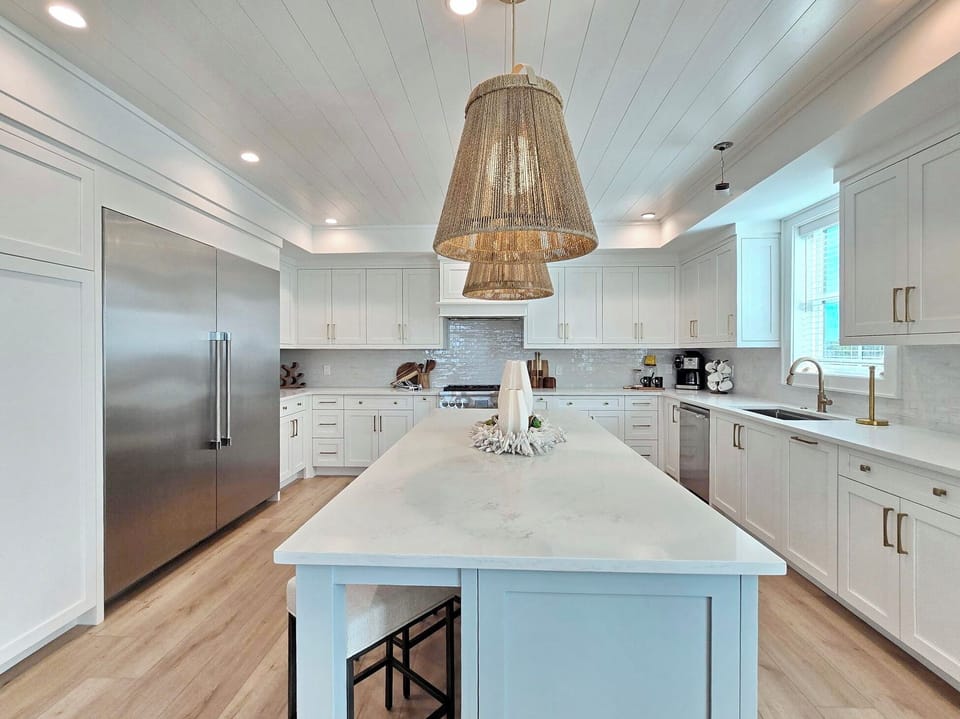 Cook gourmet meals in your stunning chef's kitchen featuring pristine white cabinetry, marble countertops, and high-end appliances.