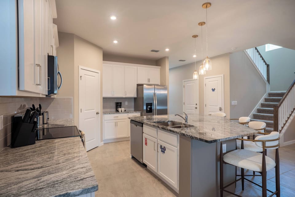 Enjoy culinary delights in this modern kitchen with shining granite countertops and bright white cabinets. Stylish bar stools encourage casual gatherings, while warm pendant lights create a welcoming atmosphere for evening meals.