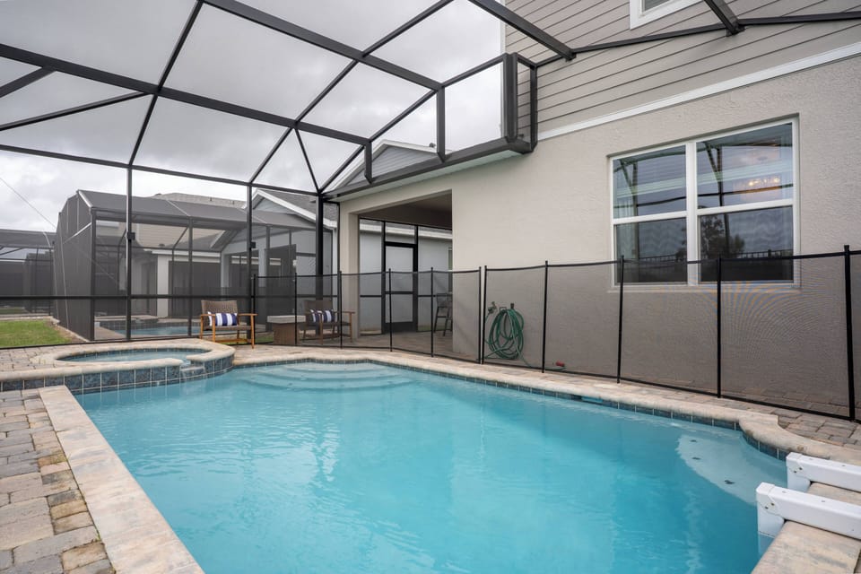 Step outside to discover your private oasis featuring a sparkling pool and stylish screened enclosure. The elegant stone patio invites relaxation, and comfy lounge chairs are perfect for sun-soaked afternoons and serene evenings.