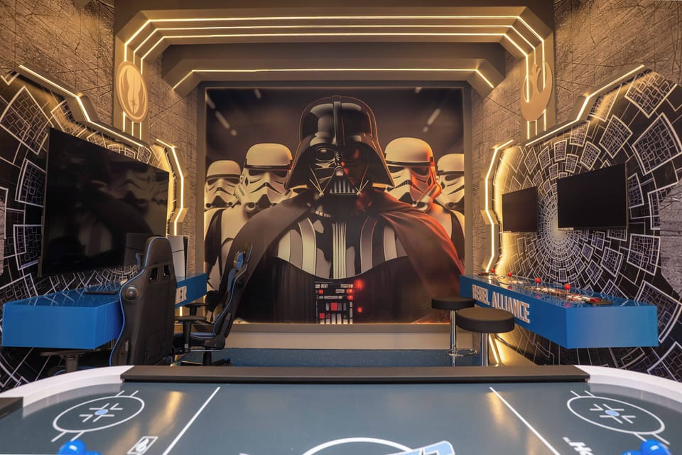 Welcome to a lively game room adorned with a striking mural of iconic characters, setting the tone for fun. With sleek blue furniture and vibrant lighting, it's the ideal spot for friendly competitions and memorable gatherings.