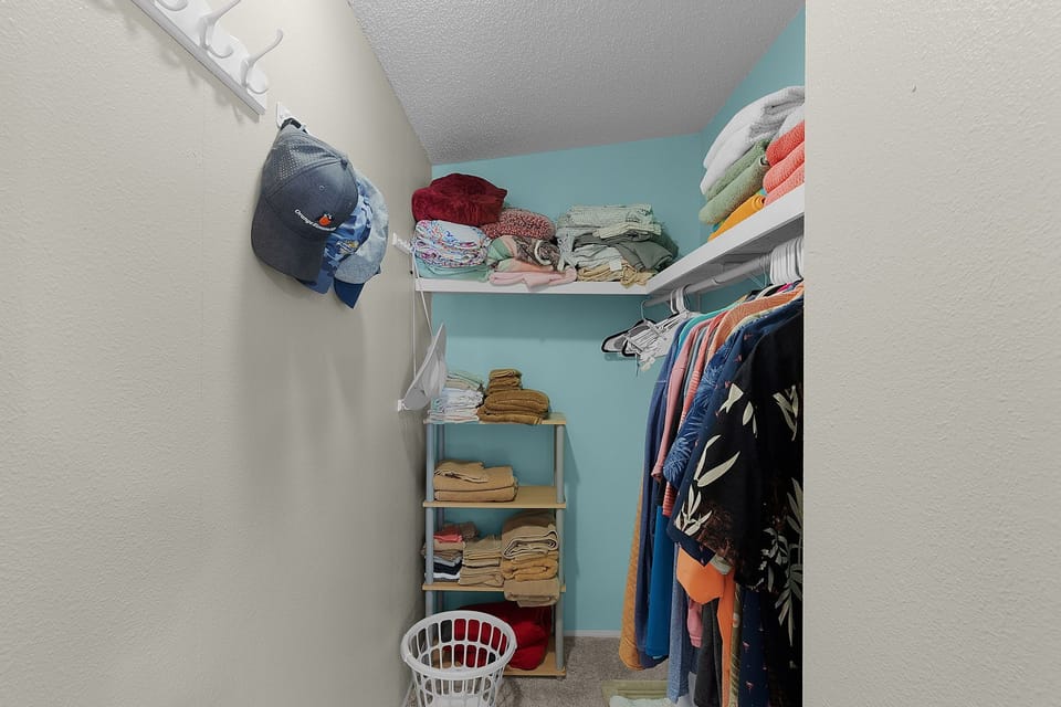 Your walk-in closet offers organized storage with shelving, hanging space, and folded towels—everything you need for an extended stay.