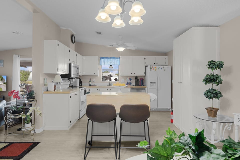 Step into your bright, open kitchen where white cabinets and warm wood counters create the perfect space for cooking.
