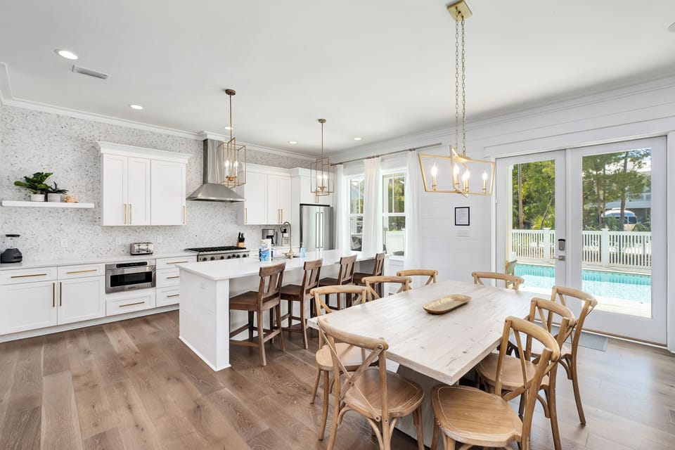 Your bright, open kitchen flows seamlessly into the dining area, where you'll gather around the rustic table with pool views beckoning through sliding doors.