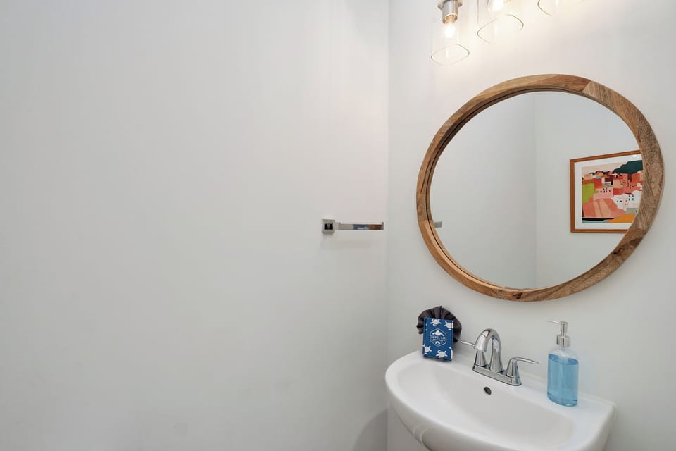 Freshen up in your bright, modern powder room with elegant wood-framed mirror and stylish fixtures.