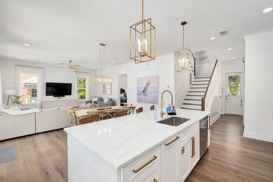 Your open-concept haven combines sleek kitchen, cozy living space, and dining area under elegant gold pendant lights—perfect for gathering and relaxation.