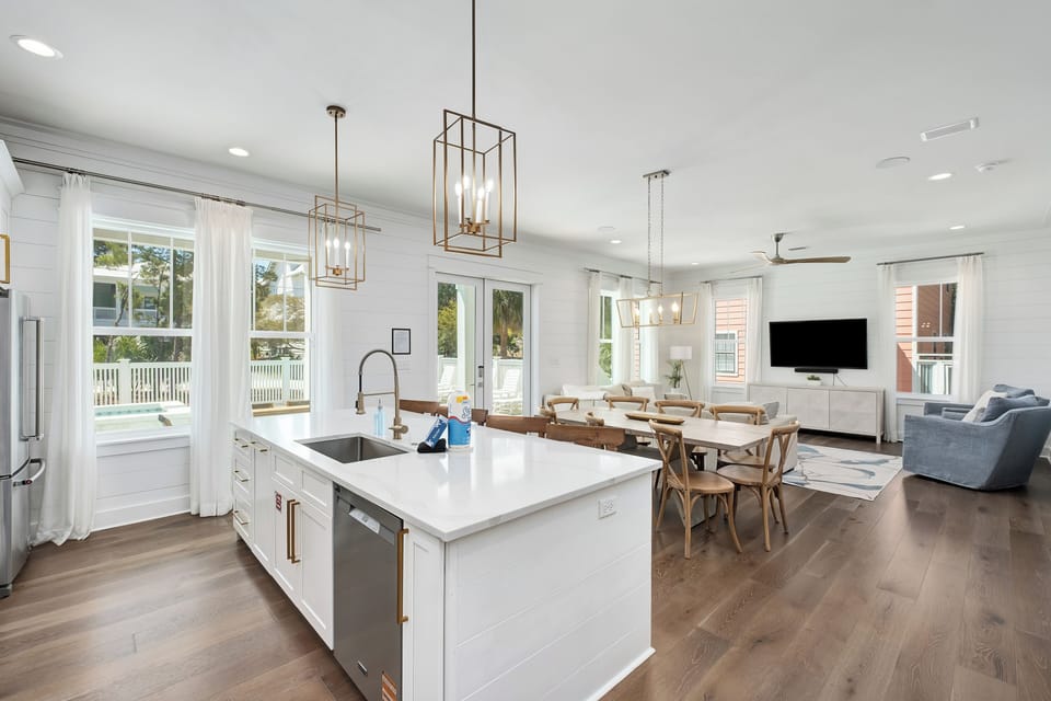 Your open-concept living flows seamlessly from kitchen island to dining table, where brass pendant lights create warm ambiance for memorable meals together.