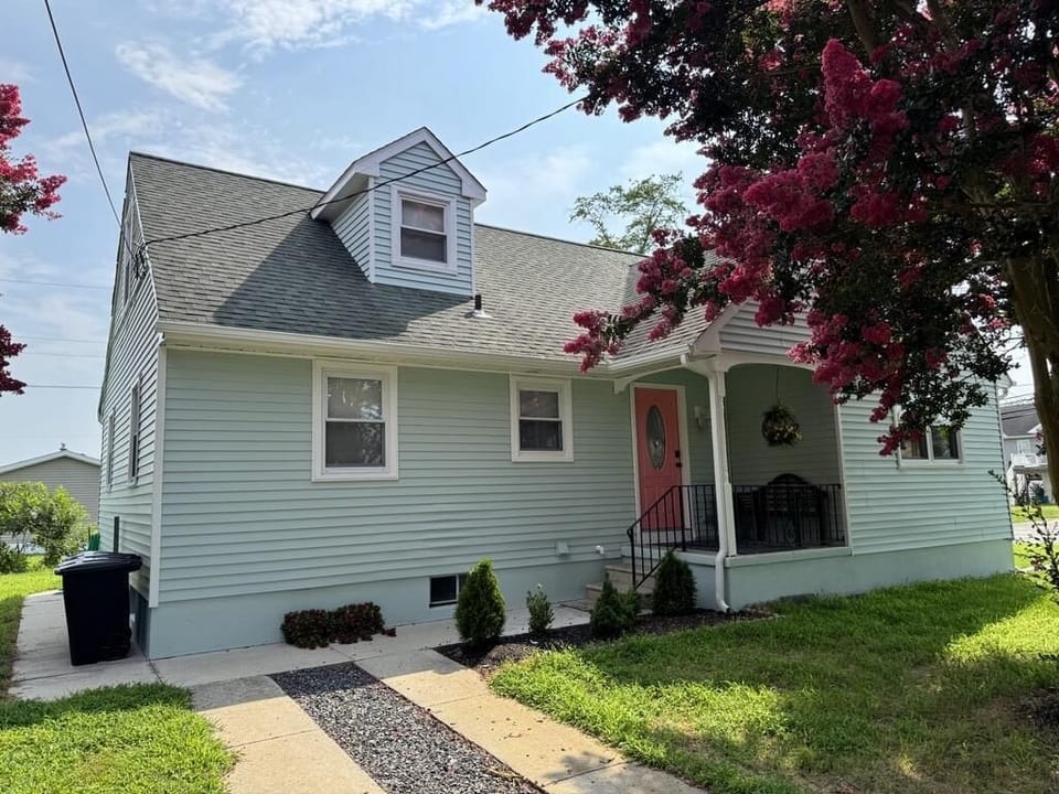 A charming home with a cozy front porch framed by pink blossoms.