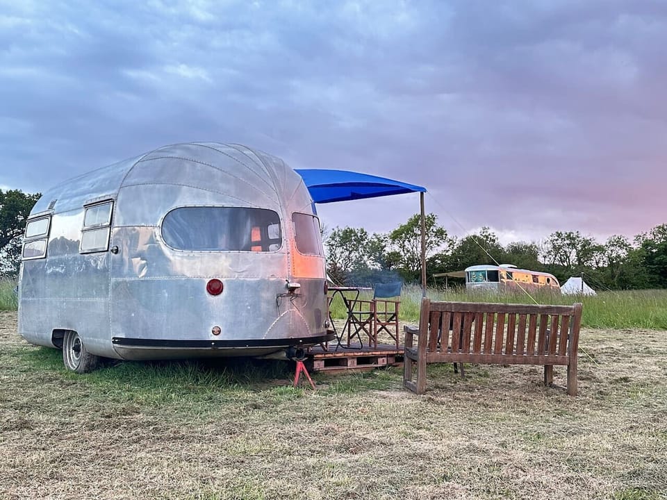 Side view of the trailer with deck seating and bench in the meadow.