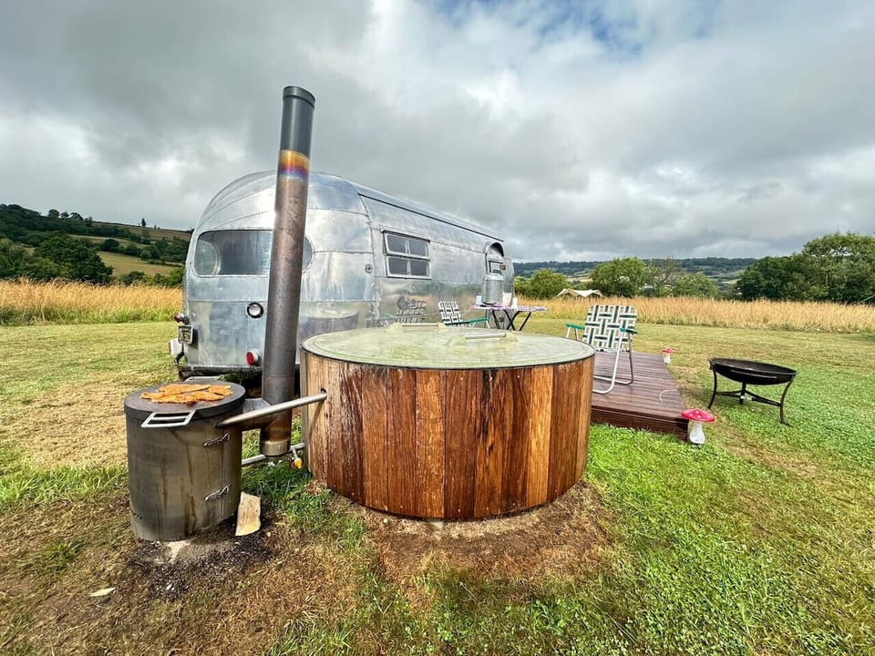 Wood-fired hot tub bubbling beside the trailer with valley views.