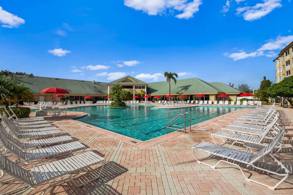 A sparkling pool surrounded by lounge chairs and shaded by vibrant umbrellas.