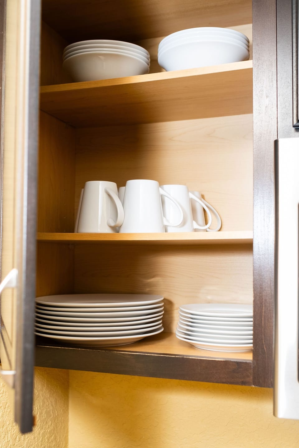 Organize your meals with ease using neatly arranged kitchen cabinets and dishware.