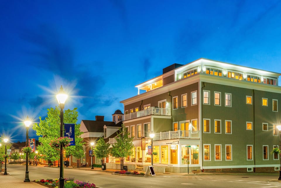 Under a vibrant evening sky, this resort beckons with its sophisticated architecture and welcoming ambiance, perfectly situated in lively downtown Kennebunk.
