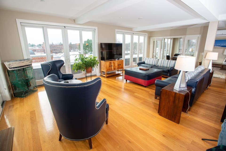 This spacious living area is bathed in natural light, showcasing stylish furnishings and large windows that provide breathtaking views of Kennebunk's charming scenery.