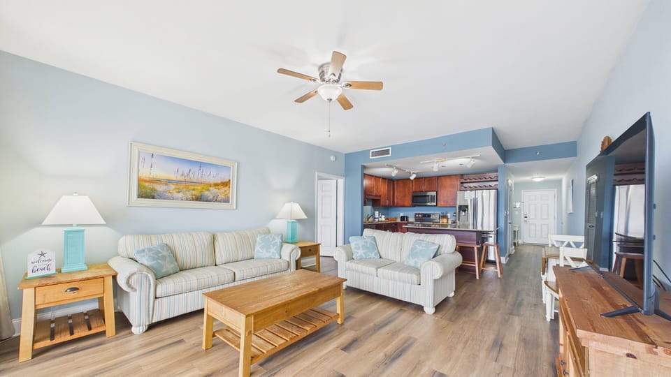 Open concept living room living area with stylish furnishing spa coastal decor paired with a TV and access to balcony