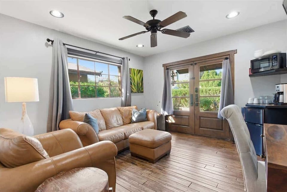 Bright and open living area featuring cozy furnishings, Smart TV, workstation with a desk and chair, mini fridge, microwave, and front yard access.