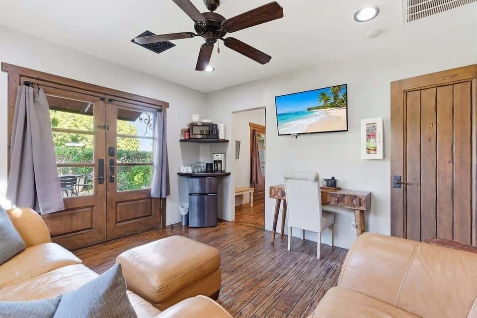 Bright and open living area featuring cozy furnishings, Smart TV, workstation with a desk and chair, mini fridge, microwave, and front yard access.