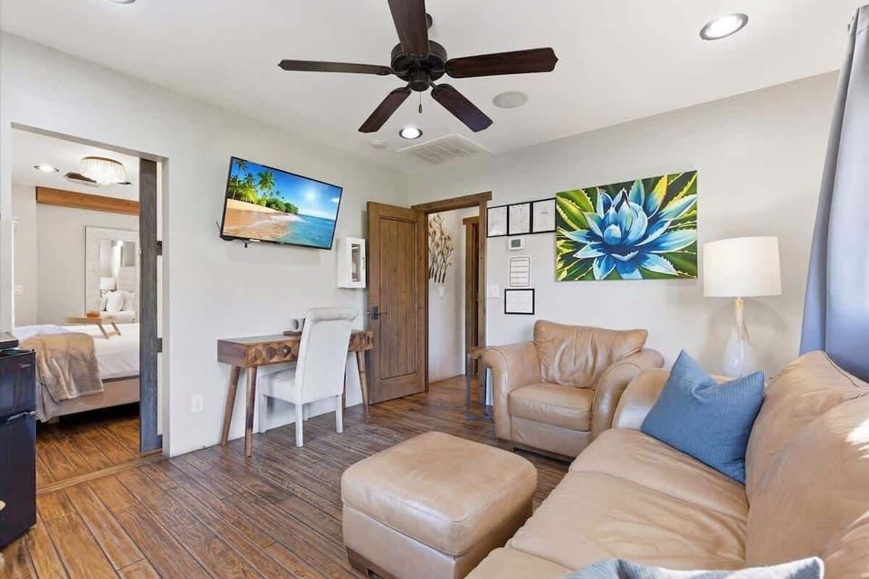 Bright and open living area featuring cozy furnishings, Smart TV, workstation with a desk and chair, mini fridge, microwave, and front yard access.