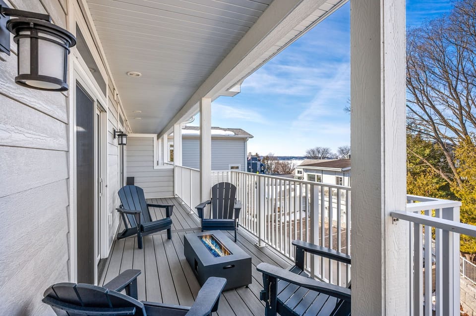 Expansive wraparound veranda with harbor views, Adirondack chairs, and a fire table, perfect for sunset evenings or morning coffee,  year-round