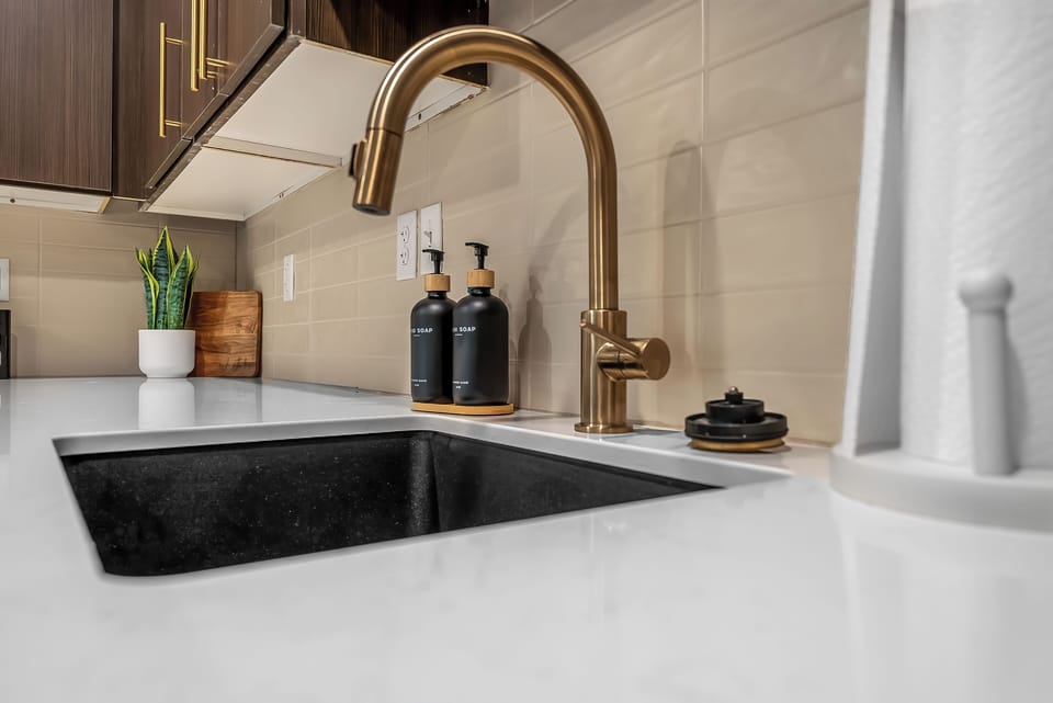 Your sleek kitchen features a stunning brass faucet and deep black sink, perfectly positioned for preparing meals with style and ease.