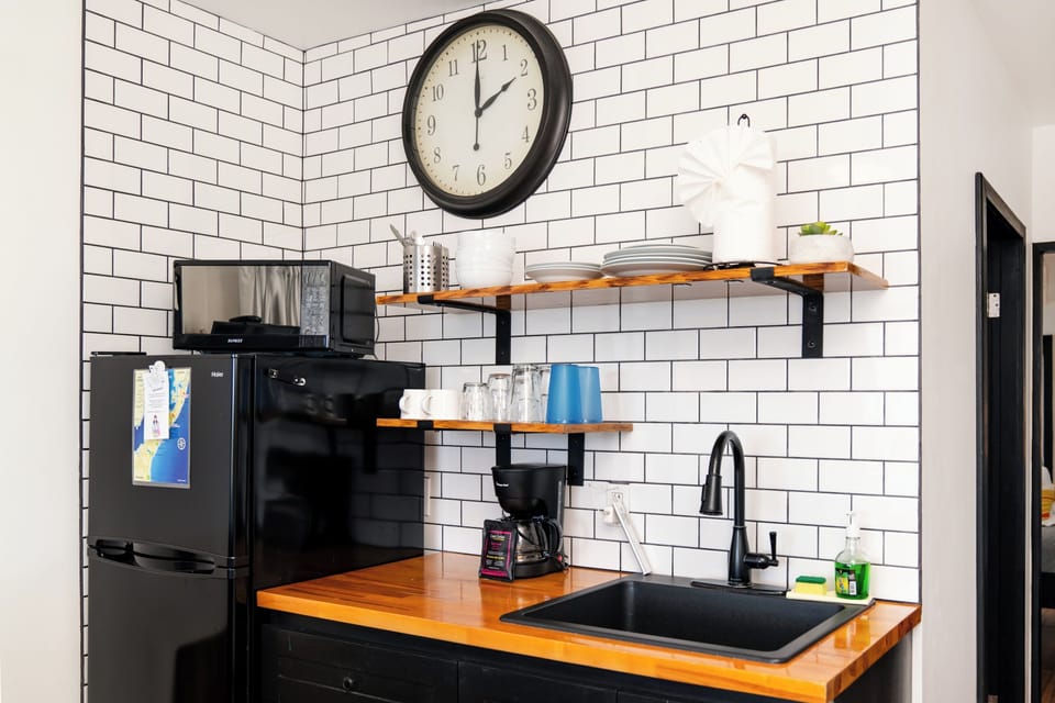 Your stylish kitchenette features sleek black appliances, warm wood countertops, and crisp subway tile walls—perfect for brewing morning coffee or prepping light meals during your stay.