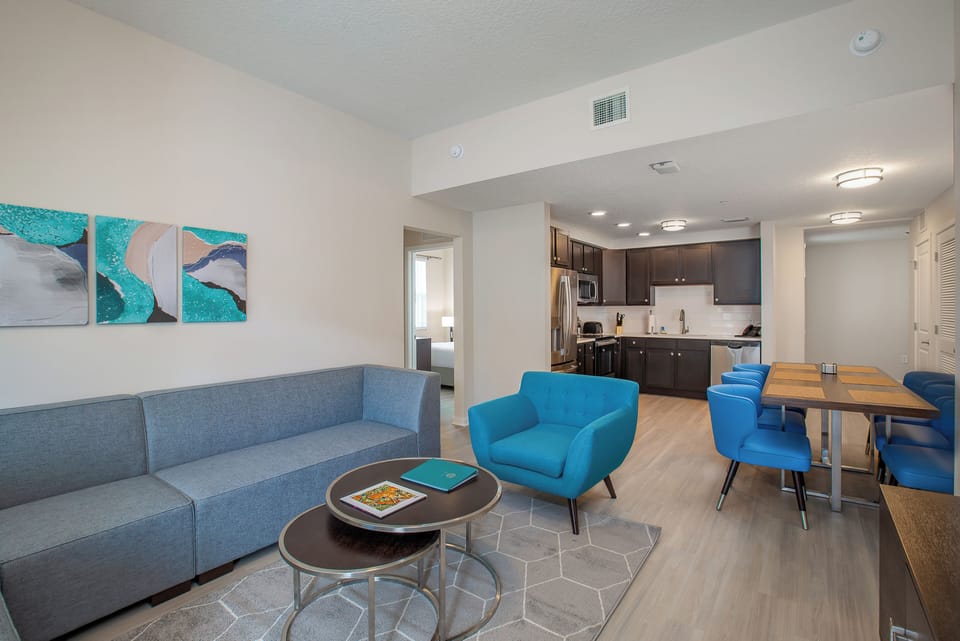 Relax in your stylish open-plan suite where vibrant turquoise accents and modern furnishings create a fresh, welcoming atmosphere for your stay.