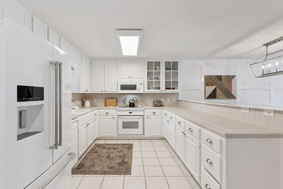 Cook memorable meals in this bright, fully-equipped kitchen featuring white cabinetry, modern appliances, and generous counter space for all your culinary adventures.