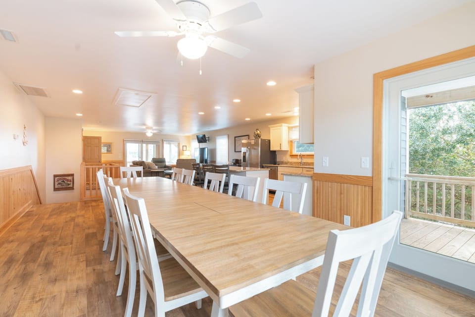 Gather everyone around this spacious dining table where memories are made over shared meals, with the open kitchen and wooded views creating perfect ambiance.