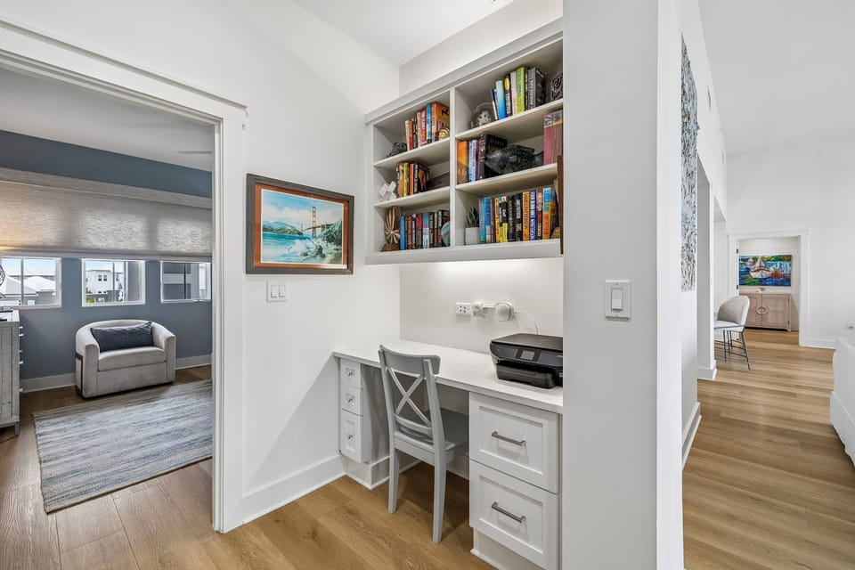 Your own quiet workspace awaits, tucked into a bright hallway with built-in desk, shelving for your favorite reads, and views into cozy rooms beyond.