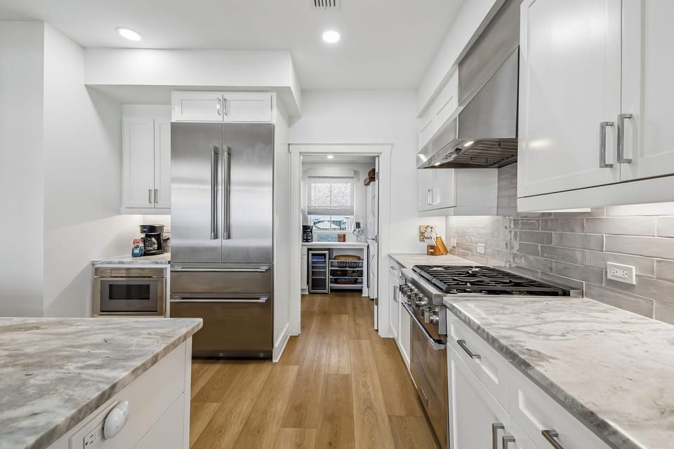 Step into your fully equipped chef's kitchen with sleek stainless appliances, marble countertops, and warm wood floors—perfect for whipping up memorable vacation meals together.