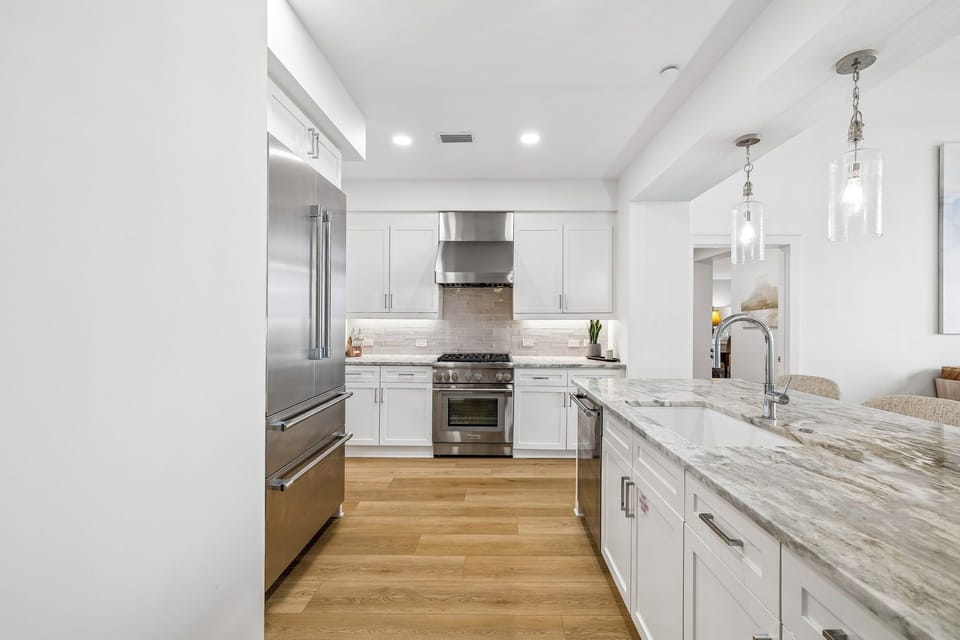 Your gourmet kitchen awaits with gleaming marble countertops, professional-grade stainless steel appliances, and elegant pendant lighting—perfect for preparing meals or gathering with loved ones.