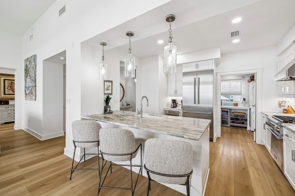 Gather around the bright kitchen island with modern bar seating, stainless appliances, and elegant pendant lighting. Your culinary adventures start here in this airy, sunlit space designed for memorable moments.