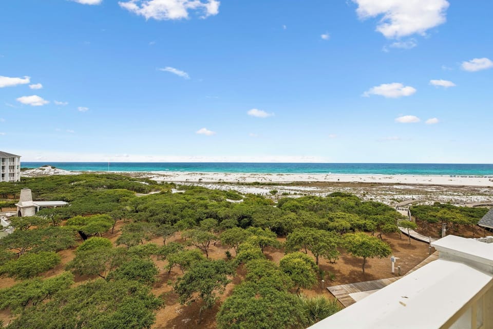Elevated view overlooking lush coastal vegetation and pristine beachfront with turquoise waters, showcasing the property's prime seaside location.