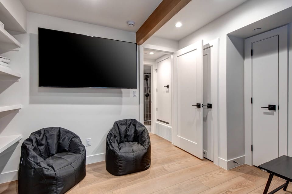 Sink into cozy bean bag chairs for movie nights on your big screen, with modern finishes and warm wood accents creating your perfect retreat.