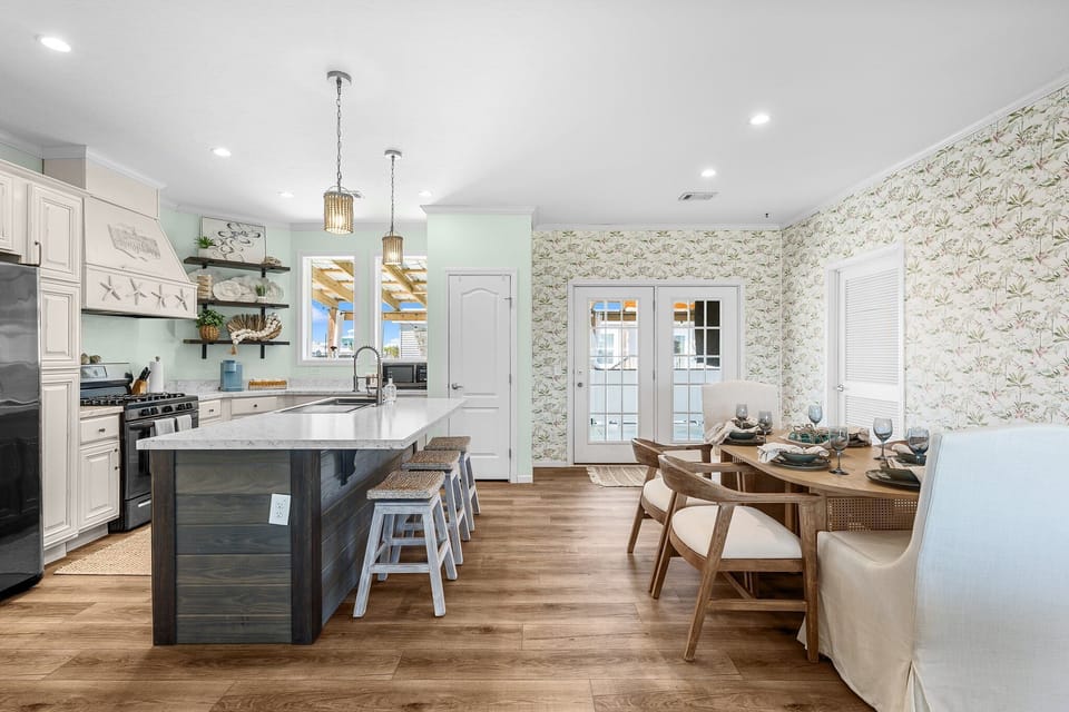 Gather around the spacious kitchen island while your meal simmers, then enjoy dinner at the elegant dining table beneath charming wallpaper.