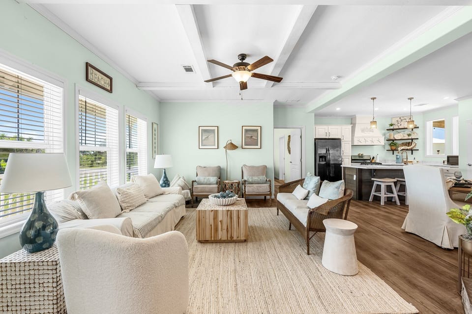 Relax in your bright, coastal-inspired living space with comfortable seating and natural light streaming through plantation shutters.