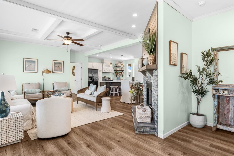 Relax in your spacious living room with soothing mint walls, cozy fireplace, and modern coastal decor that creates the perfect retreat.