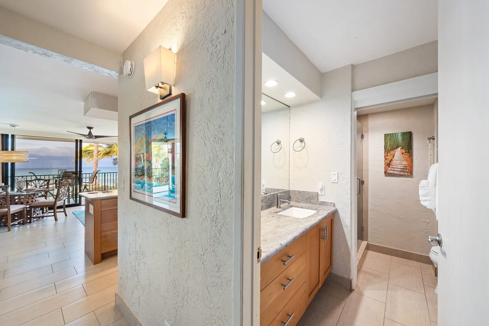 Hallway view showing seamless transition from living area with ocean view to modern bathroom with granite vanity.