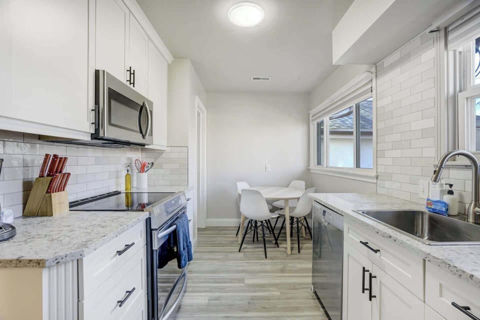 Cook and prep on speckled counters in this bright white kitchen, then gather at the dining nook by the window—perfect for easy breakfasts and chatting over coffee.
