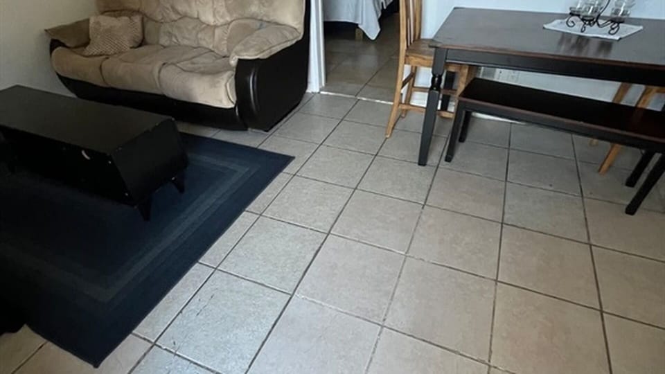 Living and dining area with sofa, table, and tile flooring