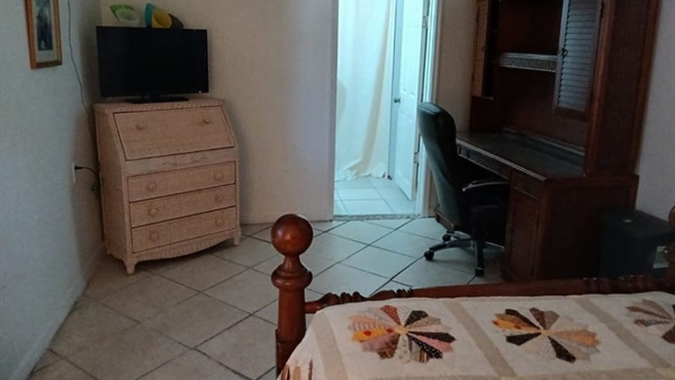 Bedroom with bed, desk, TV, and bathroom access