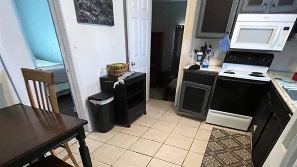 Kitchen and dining area with stove, microwave, and storage